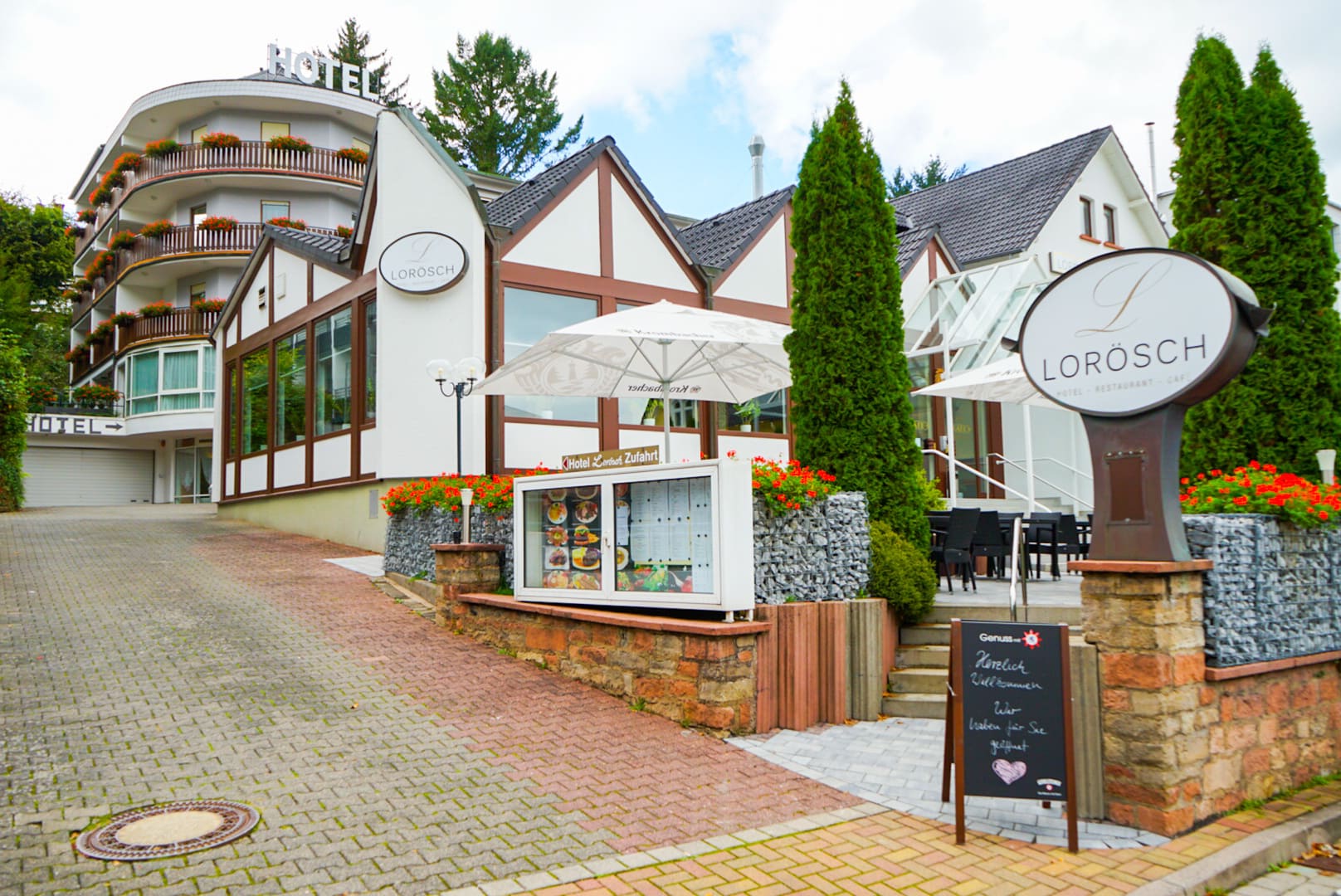 Hotel Lorösch im Sommer mit Rundbau, Terrasse und Lorösch-Schild